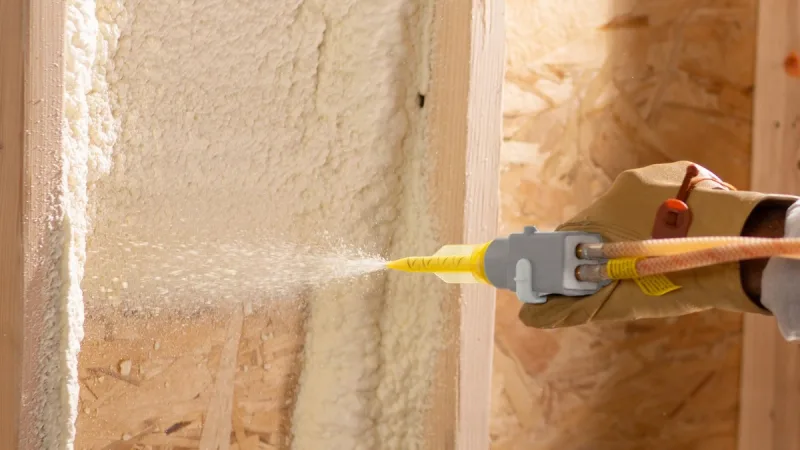 Flash coat of closed-cell foam sprayed against wall sheathing