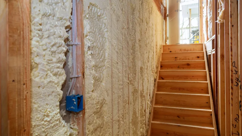 Foam filling stud bays around wiring and an outlet box before trimming